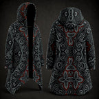 A hooded longline coat shown from the front and back on a dark studio background. The garment has an all-over ornate symmetrical pattern in black, gray, white, and red, with a black hood and black open front on the front view.