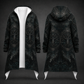 A long hooded coat shown from the front and back on a dark studio background. The coat is black with an allover dark gray gothic-style tree and geometric pattern, and features a contrasting white inner lining and white pointed hem flaps.