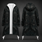 A long hooded coat shown from the front and back on a dark studio background. The coat is black with an allover dark gray gothic-style tree and geometric pattern, and features a contrasting white inner lining and white pointed hem flaps.